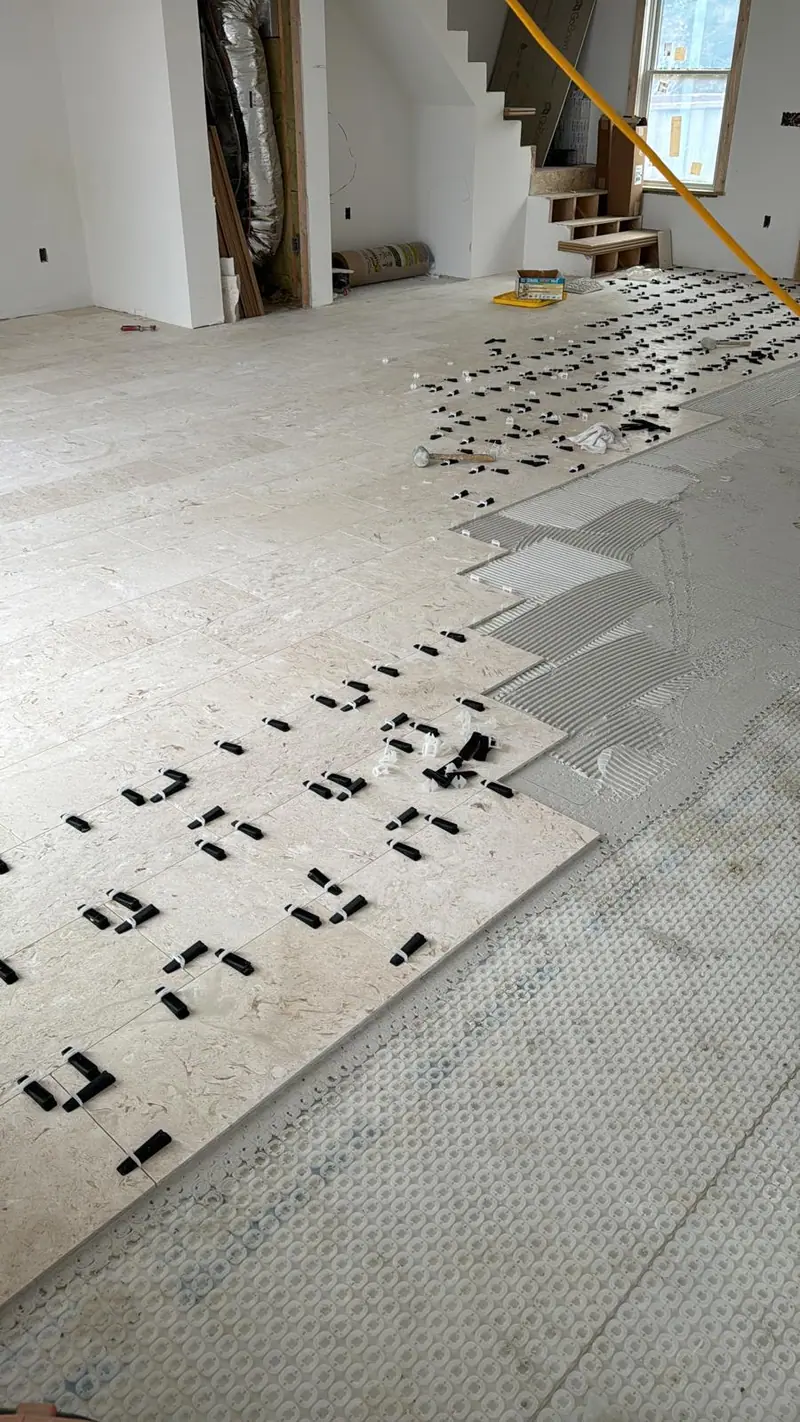 Large-format floor tiles with leveling clips laid over an uncoupling membrane